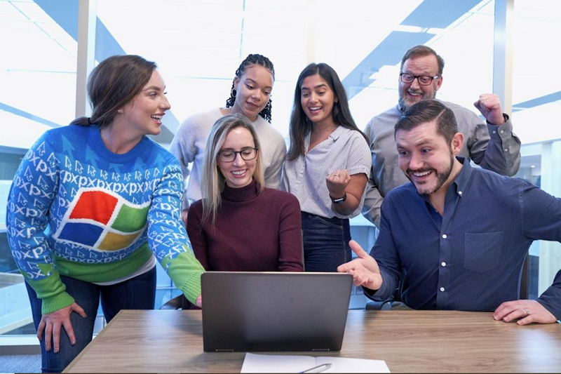 A group of professionals gathered around a table in an office conference room, working together to streamline communication and collaboration across teams