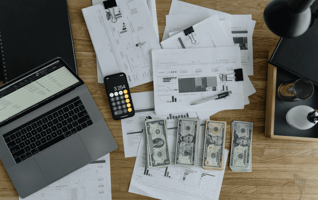 dollars on a desk with a laptop, documents and a calculator